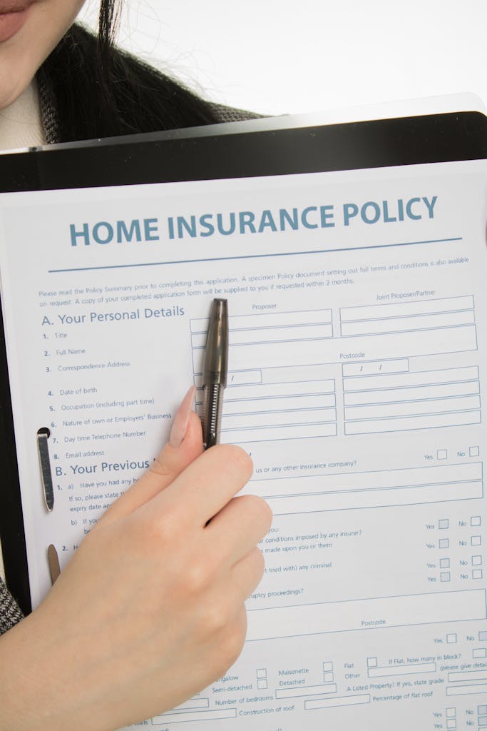 Close-up of a hand holding a home insurance policy document with a pen.